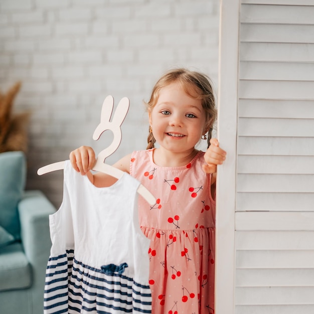 Photo une petite fille heureuse tenant une robe d'été