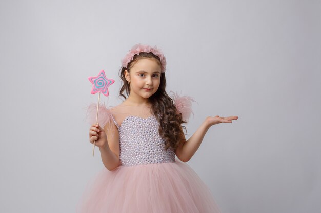 Photo petite fille à l'image d'une fée avec une baguette magique sur fond blanc