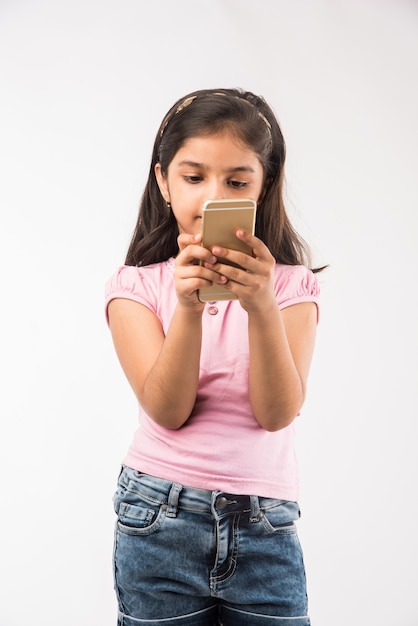 Petite fille indienne ou asiatique mignonne utilisant le smartphone, d'isolement sur le blanc