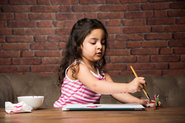 Petite fille indienne dessinant ou peignant avec des couleurs sur papier, mise au point sélective