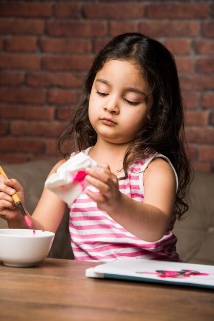 Petite fille indienne dessinant ou peignant avec des couleurs sur papier, mise au point sélective