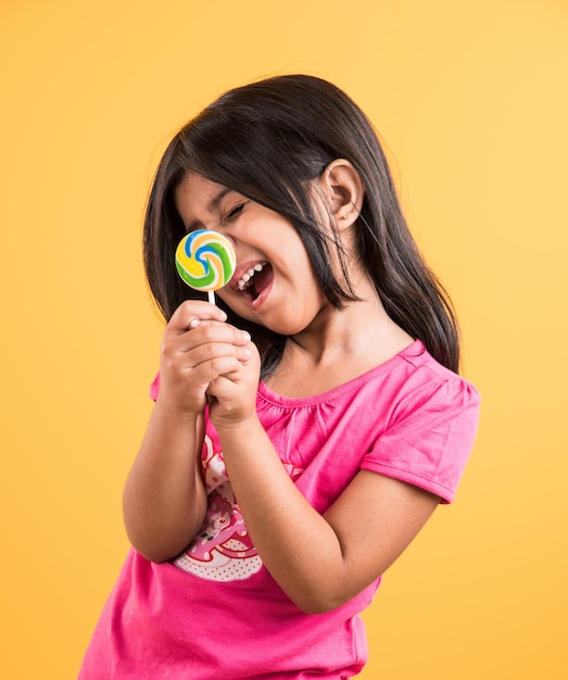 Petite fille indienne avec sucette ou loly pop, fille asiatique et sucette ou lolypop, jolie fille indienne ludique posant avec sucette ou bonbons