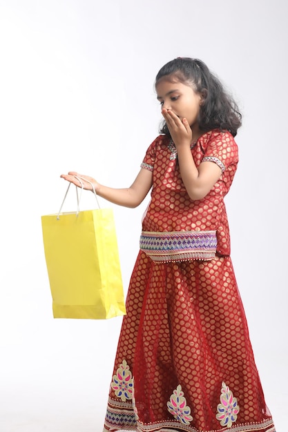 Petite fille indienne tenant un sac à provisions et donnant l'expression sur fond blanc