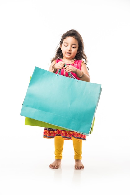 Petite fille indienne tenant des sacs à provisions, debout isolé sur fond blanc