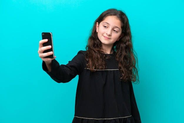 Petite fille isolée sur fond bleu faisant un selfie