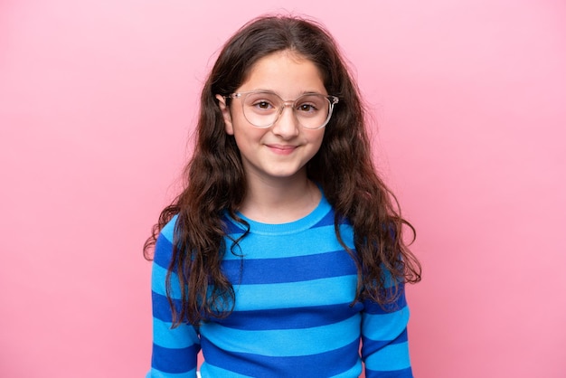 Petite fille isolée sur fond rose avec des lunettes avec une expression heureuse