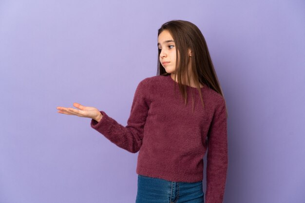 Petite fille isolée sur fond violet tenant avec des doutes