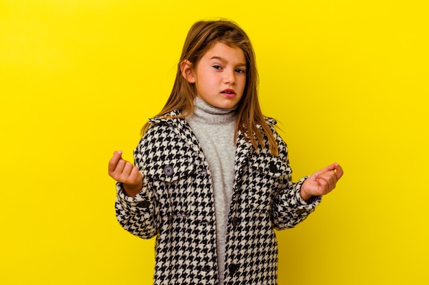 Petite fille isolée sur un mur jaune montrant qu'elle n'a pas d'argent