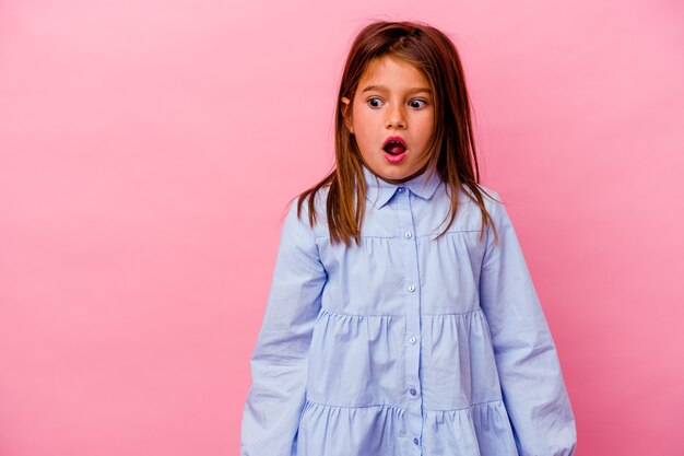 Petite fille isolée sur un mur rose choquée à cause de quelque chose qu'elle a vu