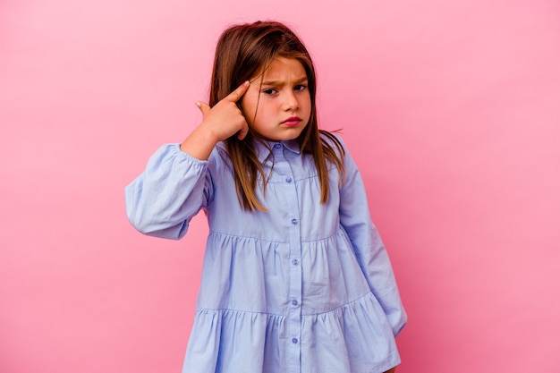 Petite fille isolée sur un mur rose montrant un geste de déception avec l'index