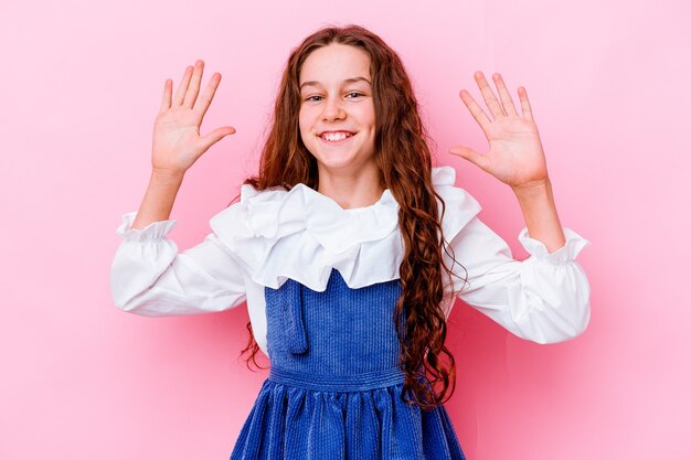 Petite fille isolée sur un mur rose recevant une agréable surprise, excitée et levant les mains