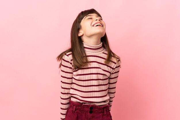 Petite fille isolée sur un mur rose en riant