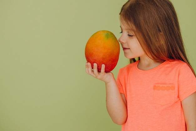 Petite fille isolée tenant la mangue