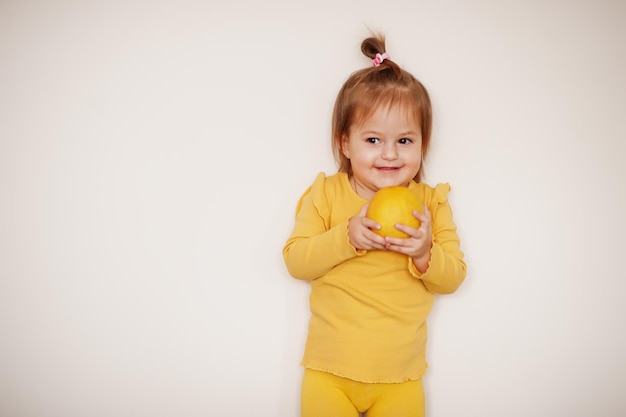 Petite fille en jaune avec du citron, fond isolé.