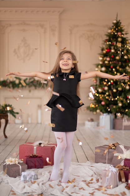 Petite fille jette des confettis. La magie de Noël. Moments joyeux d'une enfance heureuse.