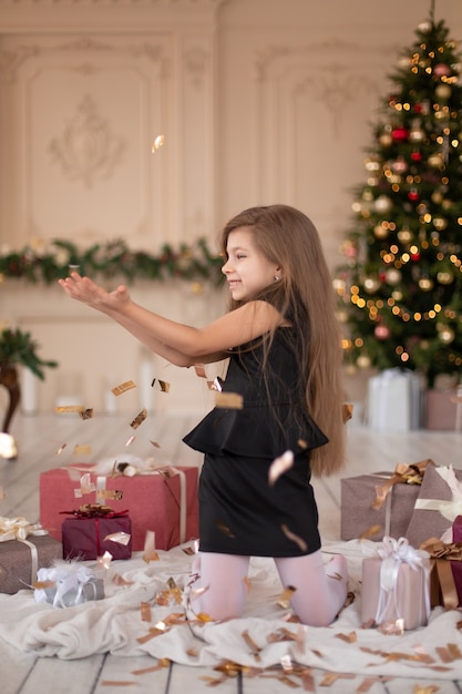 Petite fille jette des confettis. La magie de Noël. Moments joyeux d'une enfance heureuse.