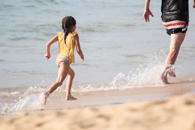 Petite fille jouait pourchasser son père sur la plage.