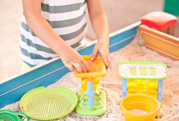 Petite fille jouant à l'aire de jeux extérieure avec du sable et des jouets