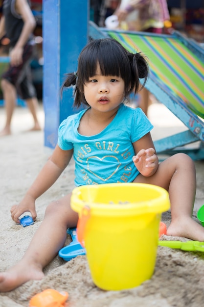 Petite fille jouant au sable sur la plage