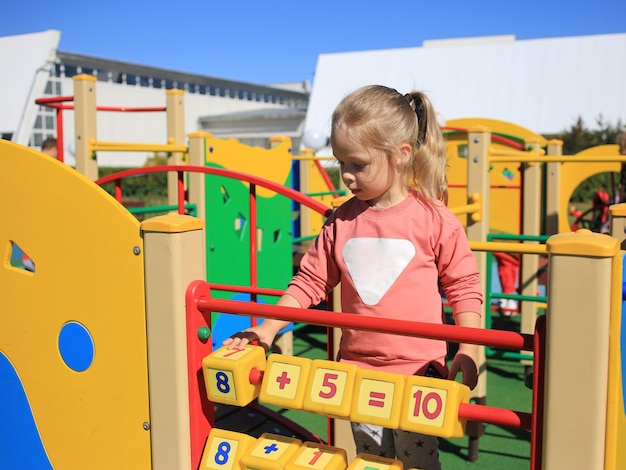 Une petite fille, jouant aux cubes avec des personnages sur une aire de jeux pour enfants.