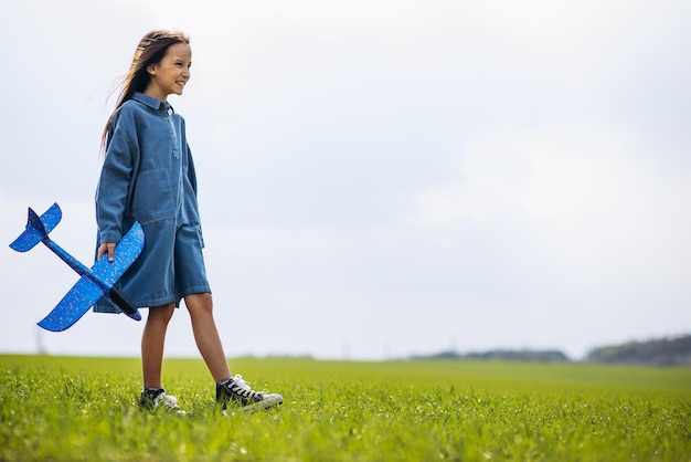 Petite fille jouant avec un avion jouet sur le terrain