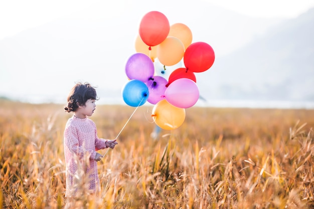 Petite fille jouant avec des ballons sur champ de blé