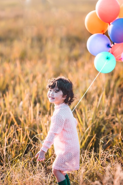 Petite fille jouant avec des ballons sur champ de blé