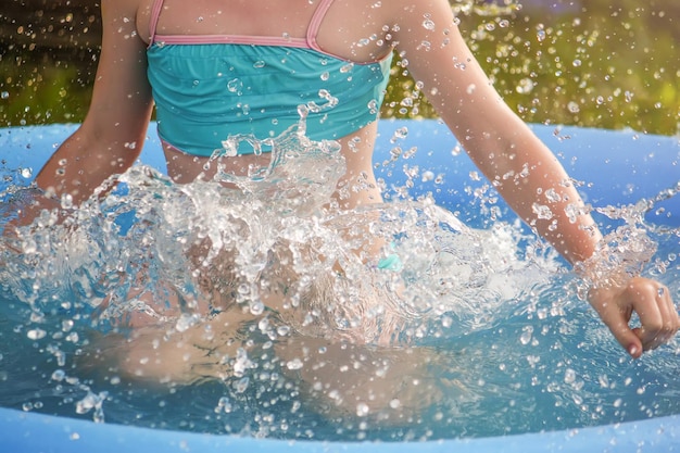 Petite fille jouant dans la piscine à l'extérieur en été