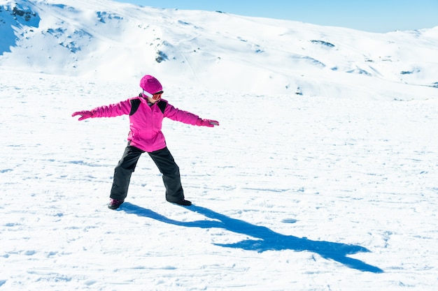 Petite fille jouant entraîneur de snowboard sur la neige