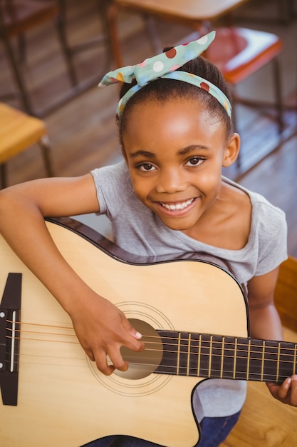 Petite fille jouant de la guitare dans la salle de classe