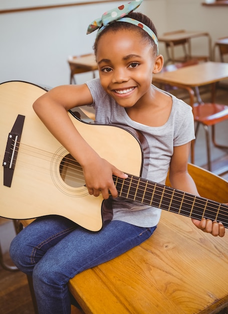 Photo petite fille jouant de la guitare dans la salle de classe