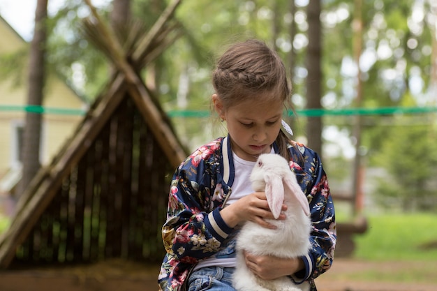 Petite fille jouant avec un lapin blanc en plein air