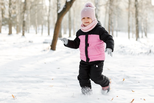 Petite fille jouant avec de la neige dans la rue