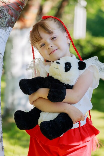 Petite fille jouant avec un panda jouet dans le parc en été. photo de haute qualité