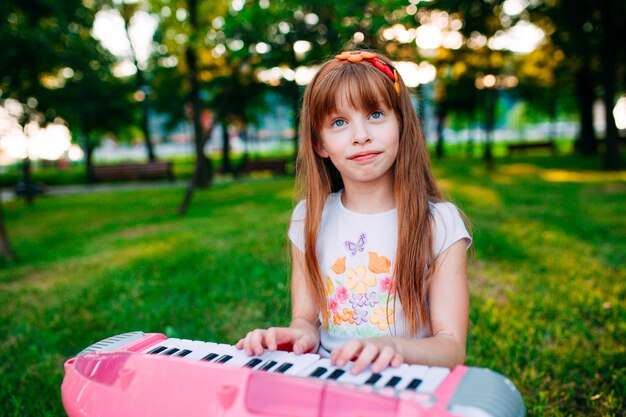 Petite fille jouant sur un piano jouet dans le parc