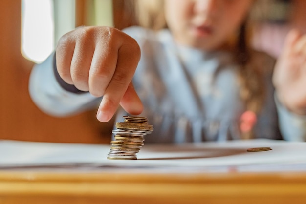 Petite fille jouant avec des pièces de monnaie faisant des piles d'argent Premières leçons de finance Accumulation Crédit enfant économisant de l'argent pour le futur concept