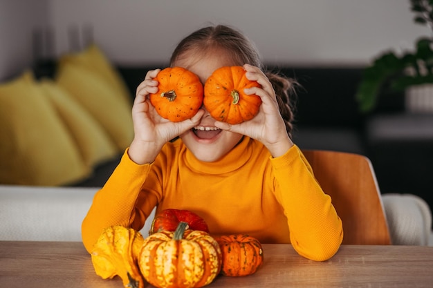 Petite fille jouant avec un portrait émotionnel de citrouille à la maison concept de fête d'Halloween