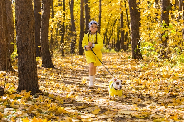 Petite fille jouant avec son chien dans la forêt d'automne