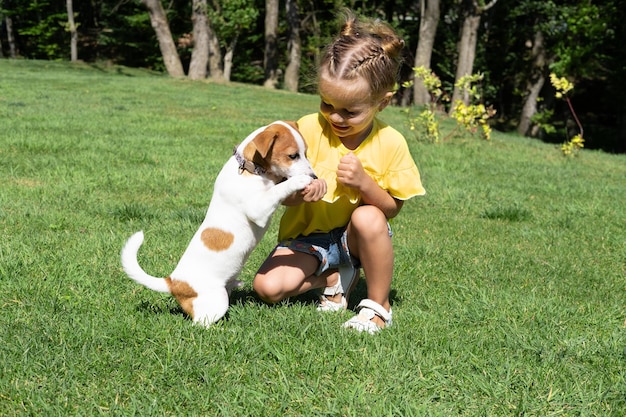 Photo petite fille jouant avec son chien jack russell terrier dans le parc