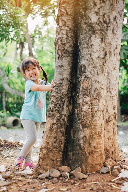 Petite fille jouant sous le grand arbre. Concept pour la nature, le réchauffement climatique et le jour de la terre.