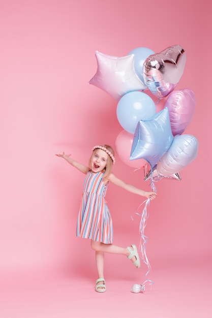 Petite fille joue avec des ballons sur une surface rose