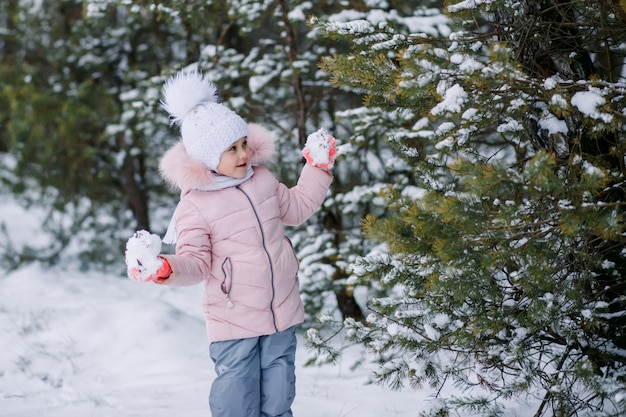 Petite fille joue des boules de neige à l'extérieur en hiver