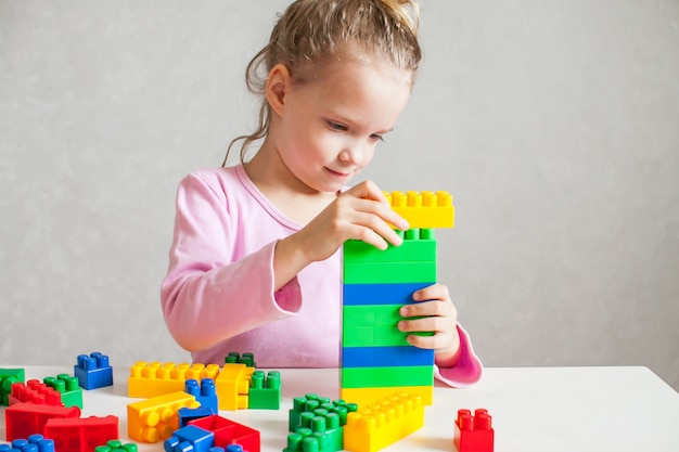 Petite fille joue avec un constructeur en plastique multicolore