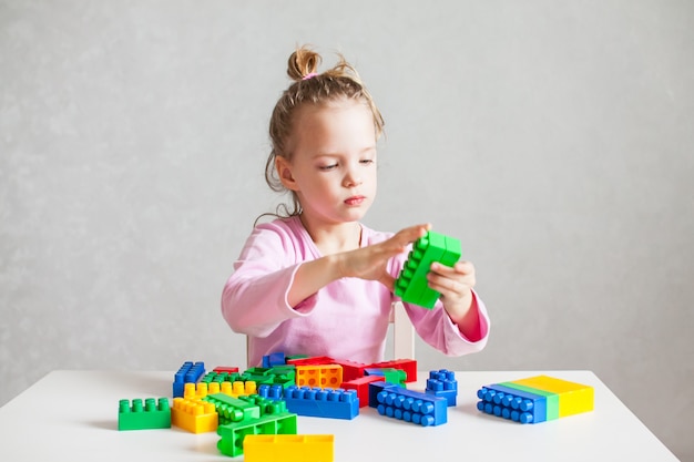 Petite fille joue avec un constructeur en plastique multicolore