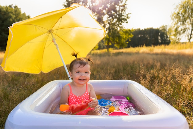 Petite fille joue dans la piscine gonflable.