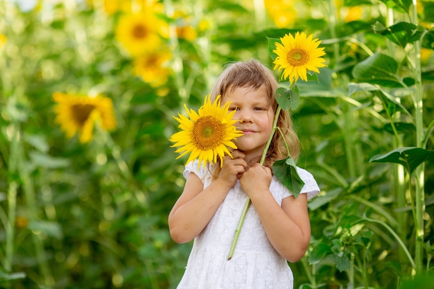 Une petite fille joue avec des fleurs de tournesol dans un champ de tournesols