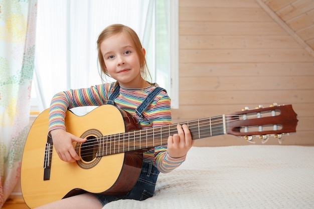Petite fille joue de la guitare à la maison.