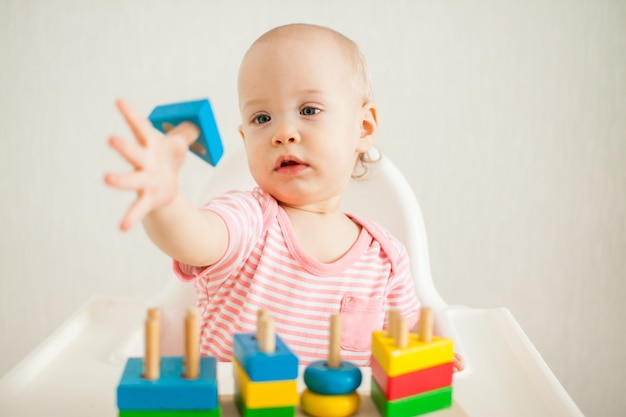 petite fille joue avec un jouet éducatif - une pyramide en bois multicolore. Développement de l'amende