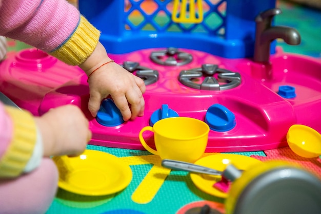 Petite fille joue avec des jouets de cuisine en plastique se bouchent