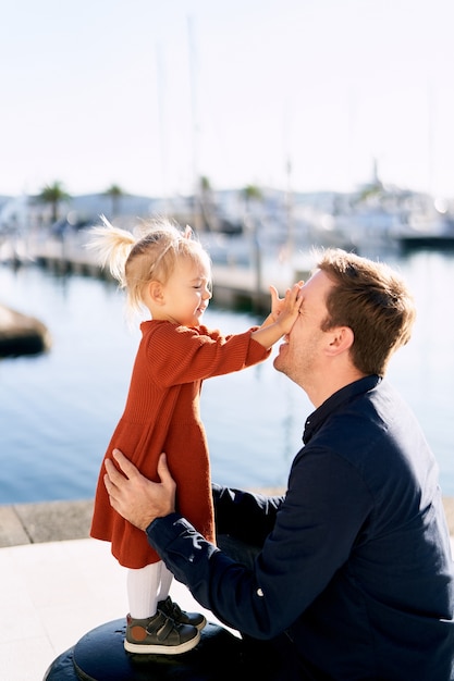 Petite fille joue à peek-a-boo avec son papa sur une marina de bateau.